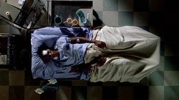 Movie still from “Paid in Full” (2002), directed by Charles Stone III – A man laying in bed with a tray of food on the floor; Wide shot, Overhead angle