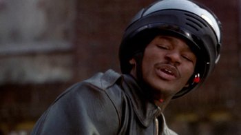 Movie still from “Paid in Full” (2002), directed by Charles Stone III – A man wearing a motorcycle helmet while riding a motorcycle; Close Up shot, Low angle