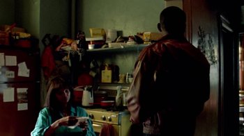 Movie still from “Paid in Full” (2002), directed by Charles Stone III – Two people in a cluttered kitchen with a stove; Medium shot, Over the shoulder angle