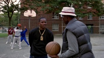 Movie still from “Paid in Full” (2002), directed by Charles Stone III – Two young men standing on a basketball court holding a ball; Medium shot, Over the shoulder angle