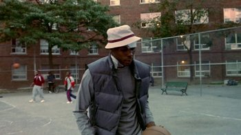 Movie still from “Paid in Full” (2002), directed by Charles Stone III – A man with a hat is holding a basketball; Medium shot, Low angle