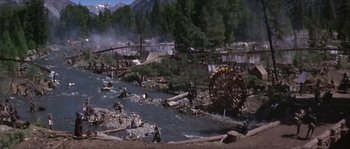 Movie still from “Paint Your Wagon” (1969), directed by Joshua Logan – A group of people standing next to a body of water; Extreme Wide shot, High angle