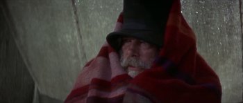 Movie still from “Paint Your Wagon” (1969), directed by Joshua Logan – An old man with a beard and a hat is wrapped in a blanket; Close Up shot, Low angle
