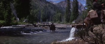 Movie still from “Paint Your Wagon” (1969), directed by Joshua Logan – A man riding a horse through a stream; Wide shot, High angle