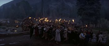 Movie still from “Paint Your Wagon” (1969), directed by Joshua Logan – A crowd of people are gathered around a bonfire; Wide shot, High angle
