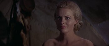Movie still from “Paint Your Wagon” (1969), directed by Joshua Logan – A woman with blonde hair and blue eyes looking at the camera; Close Up shot, Over the shoulder angle
