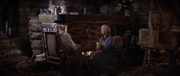 Movie still from “Paint Your Wagon” (1969), directed by Joshua Logan – An older man and woman sitting in front of a fireplace; Wide shot, Over the shoulder angle