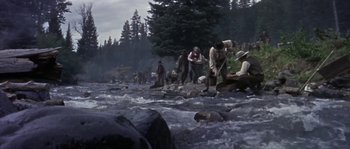 Movie still from “Paint Your Wagon” (1969), directed by Joshua Logan – A group of people standing on top of rocks in a river; Wide shot, High angle