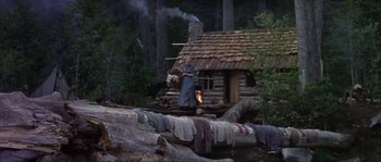 Movie still from “Paint Your Wagon” (1969), directed by Joshua Logan – A man standing in front of a log cabin; Wide shot, Low angle