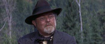 Movie still from “Paint Your Wagon” (1969), directed by Joshua Logan – An older man wearing a hat and glasses; Close Up shot, Over the shoulder angle