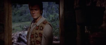 Movie still from “Paint Your Wagon” (1969), directed by Joshua Logan – A person wearing a vest near a forest; Medium shot, Over the shoulder angle