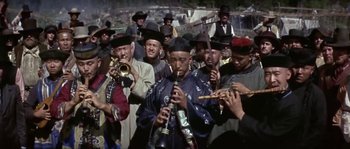 Movie still from “Paint Your Wagon” (1969), directed by Joshua Logan – A group of men playing musical instruments in front of a crowd; Medium shot, High angle