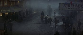 Movie still from “Paint Your Wagon” (1969), directed by Joshua Logan – A group of people walking down a street in the rain; Wide shot, High angle