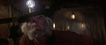 Movie still from “Paint Your Wagon” (1969), directed by Joshua Logan – An old man with a beard wearing a hat and holding a flashlight; Close Up shot, Low angle