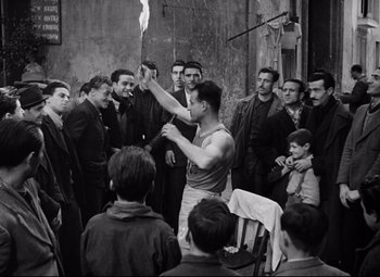 Movie still from “Paisan” (1946), directed by Roberto Rossellini – A group of men standing around a man holding something; Wide shot, Low angle