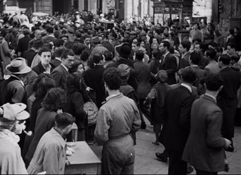 Movie still from “Paisan” (1946), directed by Roberto Rossellini – A crowd of people standing on the sidewalk; Extreme Wide shot, High angle