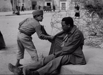 Movie still from “Paisan” (1946), directed by Roberto Rossellini – An old black and white photo of a man tying a tie; Medium shot, Over the shoulder angle