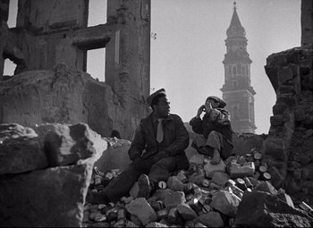 Movie still from “Paisan” (1946), directed by Roberto Rossellini – Two men sitting on the rubble of a destroyed building; Wide shot, Low angle