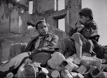Movie still from “Paisan” (1946), directed by Roberto Rossellini – A black and white photo of two men sitting on a pile of logs; Medium shot, Over the shoulder angle