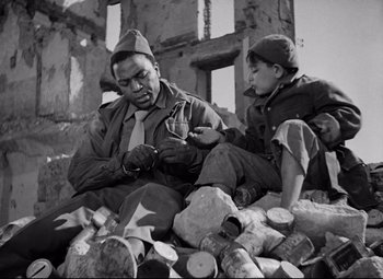Movie still from “Paisan” (1946), directed by Roberto Rossellini – A man and a boy sitting on a pile of logs; Medium shot, Low angle