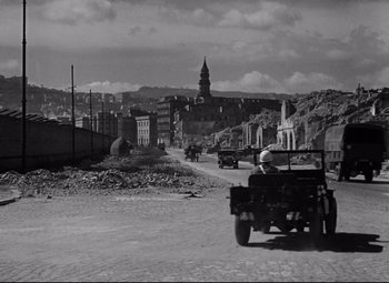 Movie still from “Paisan” (1946), directed by Roberto Rossellini – An old photo of a street with a truck driving down the road; Extreme Wide shot, High angle