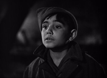 Movie still from “Paisan” (1946), directed by Roberto Rossellini – A young boy wearing a hat and a coat; Close Up shot, High angle