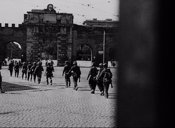 Movie still from “Paisan” (1946), directed by Roberto Rossellini – Black and white photograph of soldiers walking down a street; Wide shot, Low angle