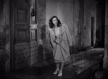 Movie still from “Paisan” (1946), directed by Roberto Rossellini – An old photo of a woman standing in the rain; Wide shot, Low angle