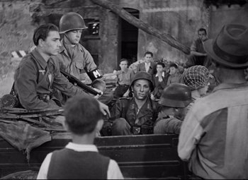 Movie still from “Paisan” (1946), directed by Roberto Rossellini – A group of men sitting on top of a truck; Medium shot, Over the shoulder angle