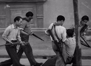 Movie still from “Paisan” (1946), directed by Roberto Rossellini – A black and white photo of a group of men walking down a street; Wide shot, High angle