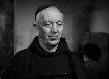 Movie still from “Paisan” (1946), directed by Roberto Rossellini – An older man wearing a monk's robe and a hat; Close Up shot, High angle