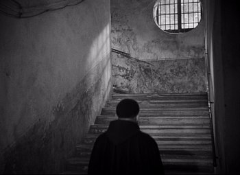 Movie still from “Paisan” (1946), directed by Roberto Rossellini – A man standing in front of a set of stairs; Wide shot, High angle
