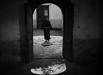 Movie still from “Paisan” (1946), directed by Roberto Rossellini – A person walking through an arched door way; Wide shot, Low angle