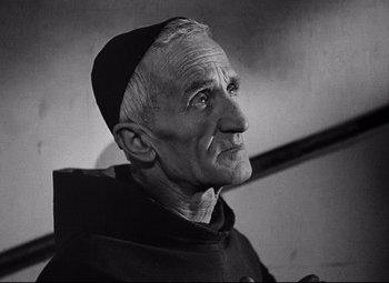 Movie still from “Paisan” (1946), directed by Roberto Rossellini – An older man wearing a black hat and a monk's outfit; Close Up shot, High angle