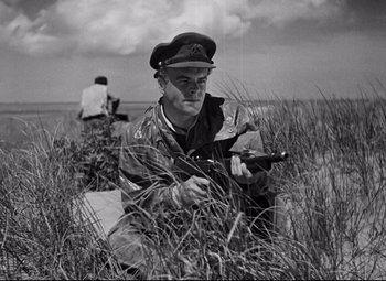 Movie still from “Paisan” (1946), directed by Roberto Rossellini – An old photo of a man with a gun in a field; Medium shot, Low angle