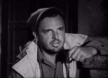 Movie still from “Paisan” (1946), directed by Roberto Rossellini – Black and white photograph of a man holding a brush; Close Up shot, Low angle