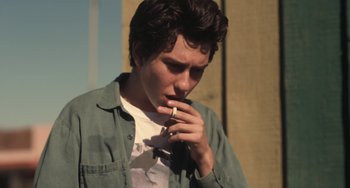 Movie still from “Palo Alto” (2013), directed by Gia Coppola – A man smoking a cigarette while wearing a shirt and tie; Close Up shot, Low angle