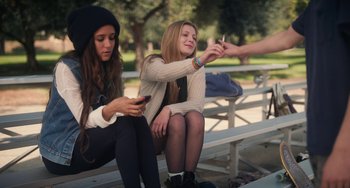 Movie still from “Palo Alto” (2013), directed by Gia Coppola – Two young women sitting on a bench looking at their cell phones; Medium shot, Over the shoulder angle