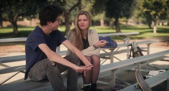 Movie still from “Palo Alto” (2013), directed by Gia Coppola – A man and a woman sitting on top of a wooden bench; Medium shot, Over the shoulder angle