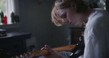 Movie still from “Palo Alto” (2013), directed by Gia Coppola – A young man is playing an electric guitar; Close Up shot, Over the shoulder angle