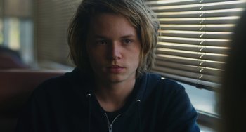 Movie still from “Palo Alto” (2013), directed by Gia Coppola – A man with long blonde hair wearing a black jacket; Close Up shot, Low angle