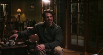 Movie still from “Palo Alto” (2013), directed by Gia Coppola – A man sitting on a chair in a living room; Medium shot, Over the shoulder angle