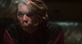 Movie still from “Palo Alto” (2013), directed by Gia Coppola – A man with long blonde hair is smoking a cigarette; Close Up shot, Low angle