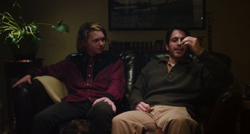 Movie still from “Palo Alto” (2013), directed by Gia Coppola – A man and a woman sitting on a leather couch; Medium shot, Over the shoulder angle
