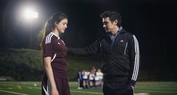 Movie still from “Palo Alto” (2013), directed by Gia Coppola – A man and a woman standing next to each other on a soccer field; Medium shot, Over the shoulder angle