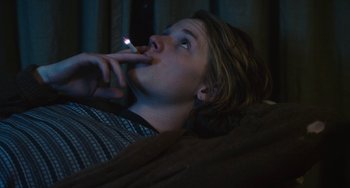 Movie still from “Palo Alto” (2013), directed by Gia Coppola – A woman smoking a cigarette while lying on a couch; Medium shot, High angle