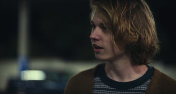Movie still from “Palo Alto” (2013), directed by Gia Coppola – A man with long hair and a striped t - shirt; Close Up shot, Over the shoulder angle