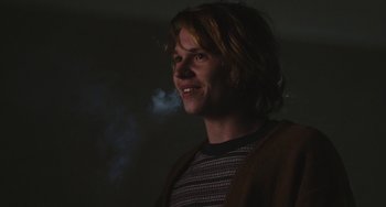 Movie still from “Palo Alto” (2013), directed by Gia Coppola – A young man is smoking a cigarette in the dark; Medium shot, Over the shoulder angle