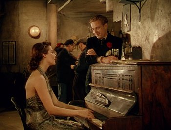Movie still from “Pandora and the Flying Dutchman” (1951), directed by Albert Lewin – A man and a woman playing a piano in a bar; Medium shot, High angle