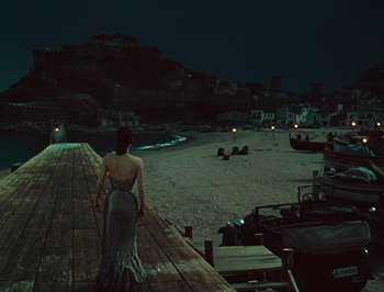 Movie still from “Pandora and the Flying Dutchman” (1951), directed by Albert Lewin – A woman standing on a pier at night; Extreme Wide shot, High angle